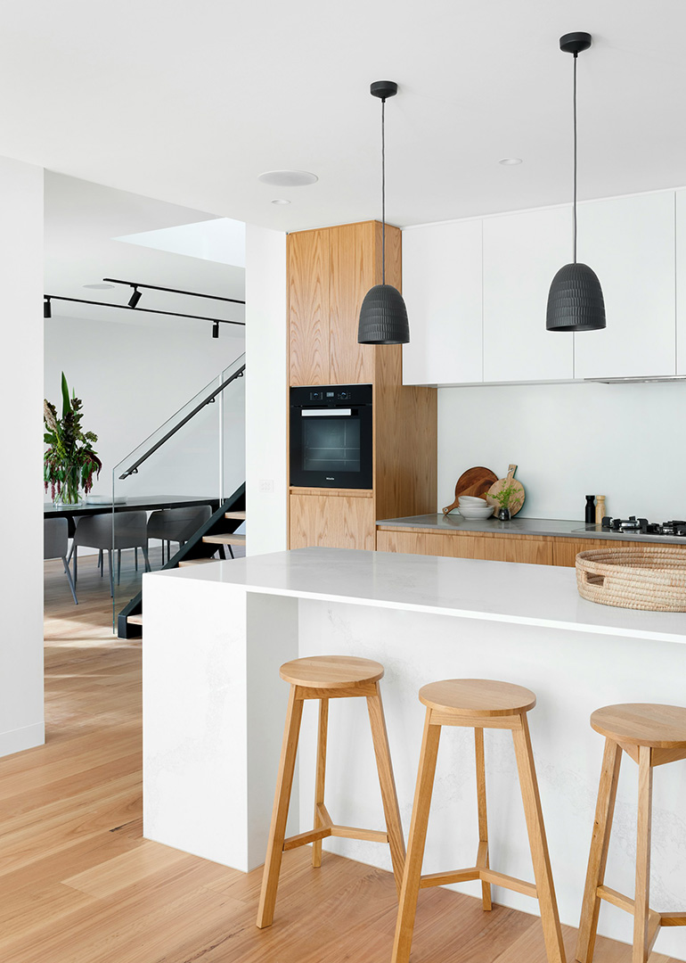 Wohnküche mit Blick auf eine Treppe. Helle, moderne Architektur mit Holz-Oberflächen.